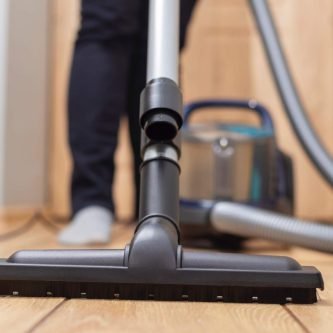 Person vacuuming wooden floor. Household chore and cleaning concept. Design for banner, poster, brochure, advertisement.